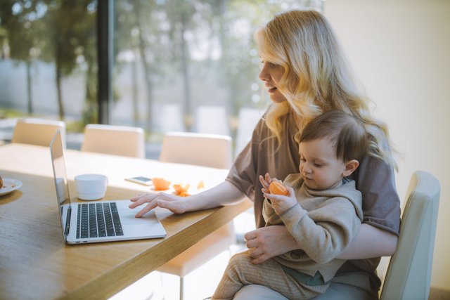 Woman Working at Home With Child on Lap